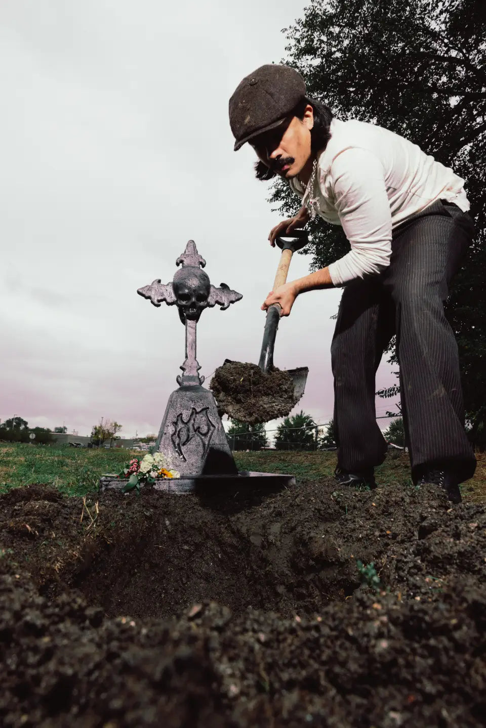 Hard Jewelry founder digging a grave beside the HJ skull-cross headstone